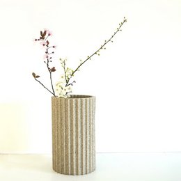 Tall, cylindrical vase in gray concrete-like material with delicate pink and purple flowers.