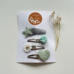 Mint and grey hair clips for kids, featuring a mix of shapes and textures including a crochet fish, heart, and daisy flowers.
