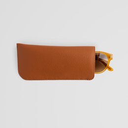 A minimalist brown leather eyewear sleeve that can hold sunglasses. The sleeve is made of high-quality leather and comes in black, brown, and grey color variants.