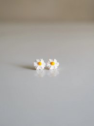 Delicate pearl earrings with white daisy flower accents, perfect for a feminine and elegant look.