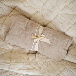 Beige linen changing mat cover with a bow detail, suitable for cushion covers.