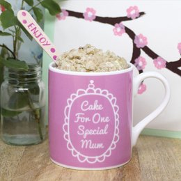 A pink ceramic mug with the text "Cake for One Special Mum" printed on it, along with a decorative floral design. The mug appears to be part of a gift set or packaging for a cake mix product.