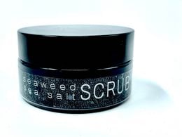 A black jar containing a seaweed-based body scrub. The scrub is designed to exfoliate and cleanse the skin, leaving it soft and refreshed.
