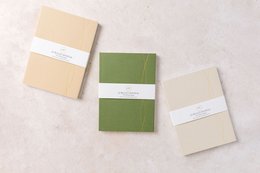 A5 bullet journals in mid green, stone, and mist colors with minimalist design and elastic closure.