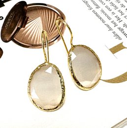 Elegant white stone cat-eye drop earrings with a gold-tone metal frame.