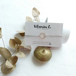 Silver-toned charm bracelet with a round, gold-colored charm featuring a decorative pattern.