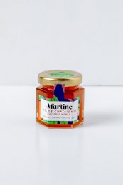 Chestnut honey in a glass jar with a red and blue label. The honey has a rich, amber color and appears to be a high-quality, artisanal product.