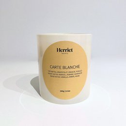  Carte Blanche scented candle in a white container with a yellow label. The candle is made of high-quality materials and has a clean, elegant design.