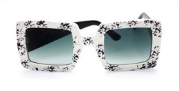 Stylish white and black sunglasses with a floral print pattern. Square-shaped frame with gradient lenses.