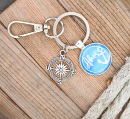 Keychain with compass and globe charms in blue, turquoise, and pink colors.