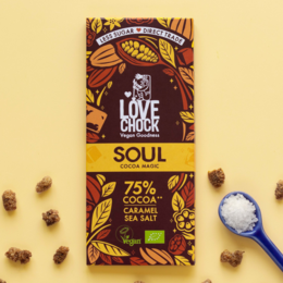 Dark chocolate bar with caramel and sea salt, organic and vegan. Broken pieces of chocolate bar with cocoa beans and nuts.