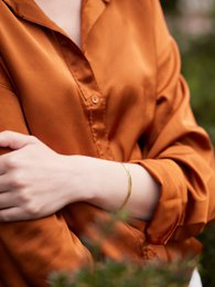 Wide Charon bracelet made of metal with a golden finish. Features a simple, minimalist design.