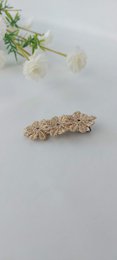 A decorative hair clip made of gold-colored metal with a floral design, suitable for children's hair accessories.
