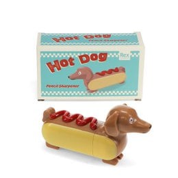 A whimsical pencil sharpener in the shape of a hot dog, with a retro-style packaging design featuring the text "Hot Dog" and a stylized illustration of the product.