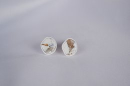 White and metallic stud earrings with a round, minimalist design.