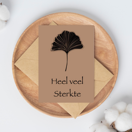 A black and gold ginkgo leaf with the text "Heel veel sterkte" which means "Wishing you much strength" in Dutch. This condolence card features a simple yet elegant design, making it suitable for expressing sympathy and support during difficult times.