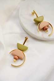 Contrast in nude and olive green drop earrings with a unique circular design and gold accents.