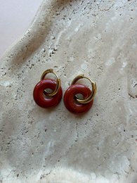 Red twisted knot stud earrings, gold accents, modern geometric design.