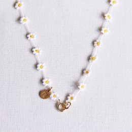 A delicate white and yellow daisy flower necklace with a minimalist design featuring small pearl-like beads and a charm pendant.