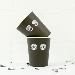 Black cardboard cup with white eyes printed on it.