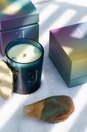 This gift set includes an opal and aquamarine candle in a dark blue container, along with a natural stone. The candle has a soft, soothing glow and the set is packaged in a colorful, gift-ready box.