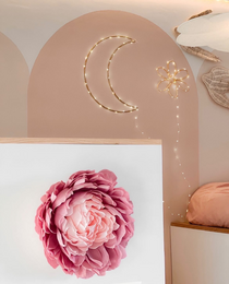 Decorative moon-shaped night light with warm, ambient lighting. Features a soft, pink floral accent.