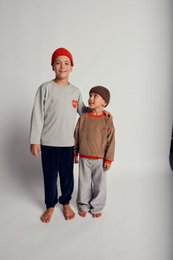  Gray long-sleeved t-shirt with red heart graphic, navy blue pants, red beanie.