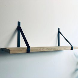  A black metal book stand with a triangular design, made of a wooden shelf and black metal supports.