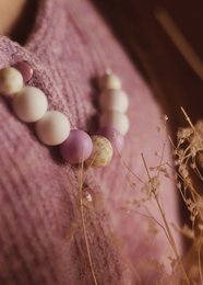 A necklace with white and pink beads, featuring a mix of round and irregular shapes. The necklace appears to be made of natural materials and has a soft, organic aesthetic.