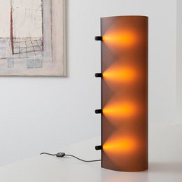 Tall, cylindrical table lamp with a chocolate brown finish and a warm, glowing light effect.