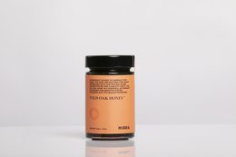 Raw, unprocessed honey in a glass jar with a black lid. The honey has a warm, amber color and is labeled as "NIRRA WILD OAK HONEY 250 grams".
