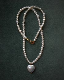 A delicate pearl necklace with a heart-shaped pendant, featuring a string of small pearls and a larger pearl at the center.