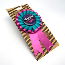 Colorful, striped buttons with text "Geboren in den 50er" and "Geboren in den 60er" indicating decade of birth. Circular award ribbons in vibrant pink and orange colors.