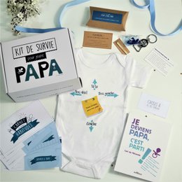 "A gift box for a new dad, containing various items to help him in his role as a father. The box is labeled 'Kit de survie pour papa' (Survival kit for dad) and includes items like a onesie, a notebook, and other accessories."