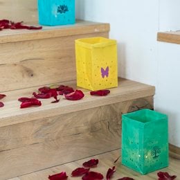 Colorful tea light holders with butterfly and paw print designs. Made of glass in various vibrant shades.