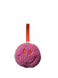  A pink, plush, round accessory for a pacifier, featuring a smiley face design. The accessory is made of soft, textured material and has an orange hanging loop.