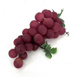 Red and purple artificial grapes bunch, realistic round berries with green leaves, decorative fruit cluster.