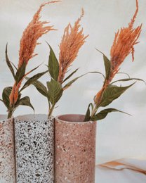 Tall cylindrical vases, speckled terrazzo texture, white and rose pink, modern minimalist style, dried flowers arrangement.