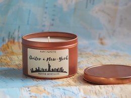 Vegetable-based scented candle with a blueberry muffin fragrance, featuring a New York City skyline design on the tin.