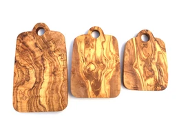 Olive wood cutting board with hole, available in 21 cm, 24 cm, and 30 cm sizes. The board features a natural, rustic wood grain pattern.