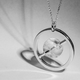 A silver-toned pendant featuring a round, clear crystal or quartz stone suspended within a circular frame.