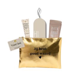 Toiletry bag in gold color with text "Goud Waard" and various bath products inside, including a bath salt container and a hand cream.
