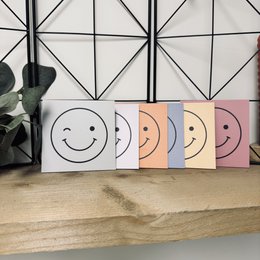 Colorful ceramic tile with smiley face design, decorative wall art in multiple pastel colors.