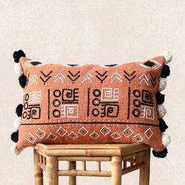 Decorative pillow case with a tribal-inspired pattern featuring tigers, geometric shapes, and pom-pom accents in shades of orange and black.