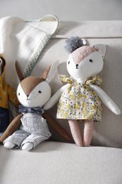 Soft, cuddly plush toy in the shape of a rabbit or bunny, with a yellow floral dress and gray and white striped overalls. The toy has a sweet, friendly expression and appears to be a children's or baby's stuffed animal.