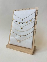 Gold delicate chain necklaces, wooden stand display, minimalist jewelry organizer, multiple layered chains.