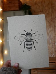 Grass paper notebook with a bee illustration. Eco-friendly notebook made from sustainable grass paper material.