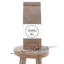 A brown paper bag with the text "QuoTEA Friends tea" printed on it, along with a decorative label. The bag appears to contain tea or a tea-related product.