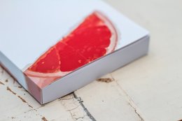 A6 notebook with a grapefruit design on the cover, featuring a bright red grapefruit slice against a white background.
