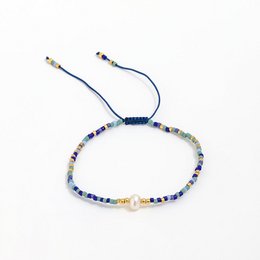Miyuki pearl bracelet with multicolored beads in various shades of blue, green, and neutral tones. Adjustable cord closure.